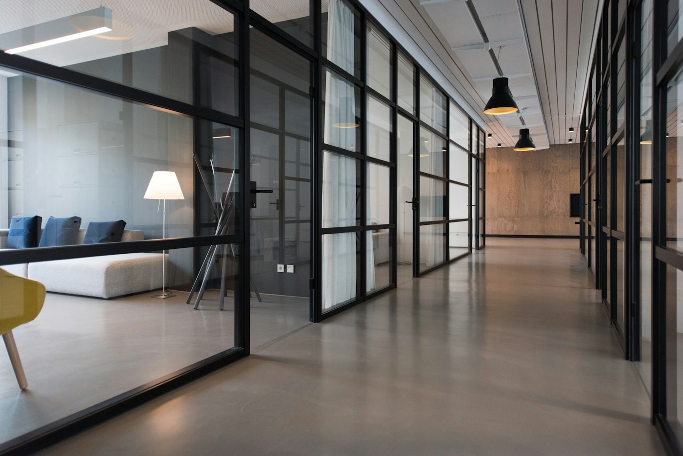 Modern office corridor lined with black-framed glass partitions
