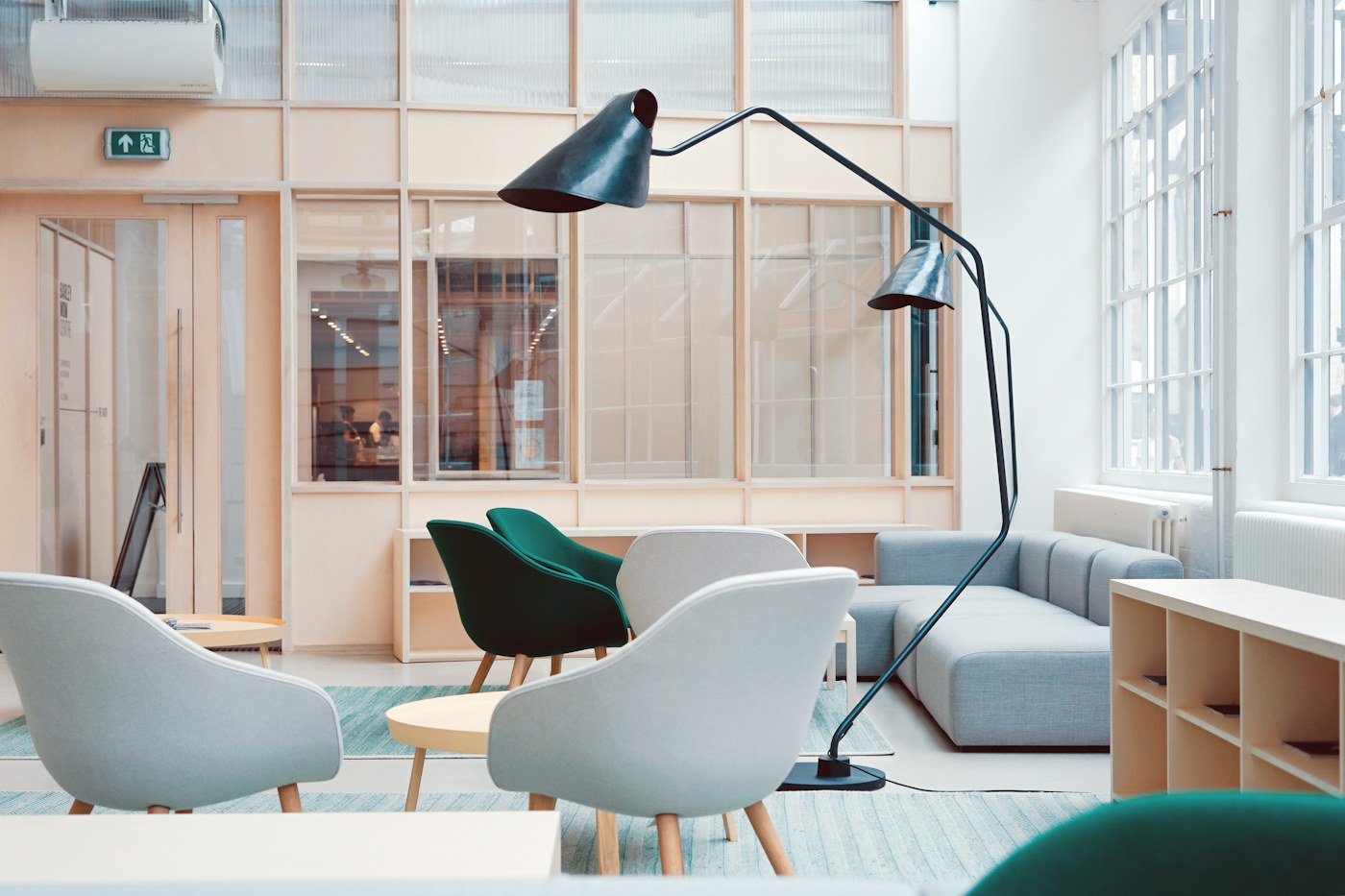 Bright open lounge with pale chairs, sofa and a tall floor lamp