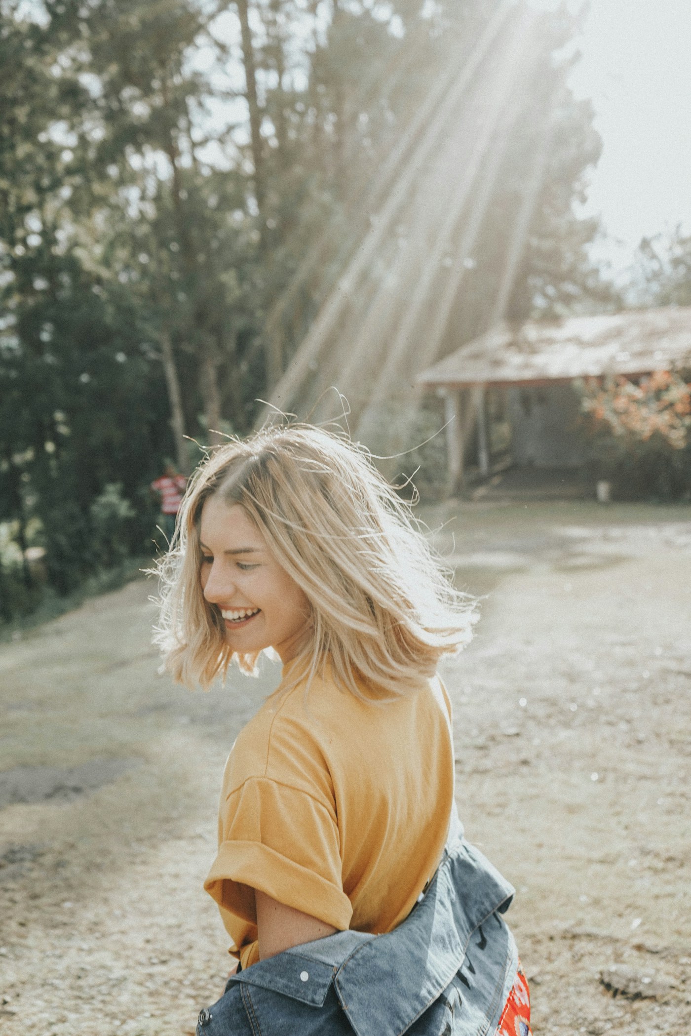 Woman with blonde hair walking outdoors in low sun rays, smiling over her shoulder
