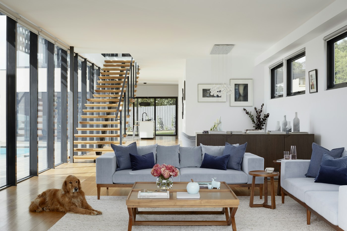 Bright living room with grey sofas, a staircase and a resting dog